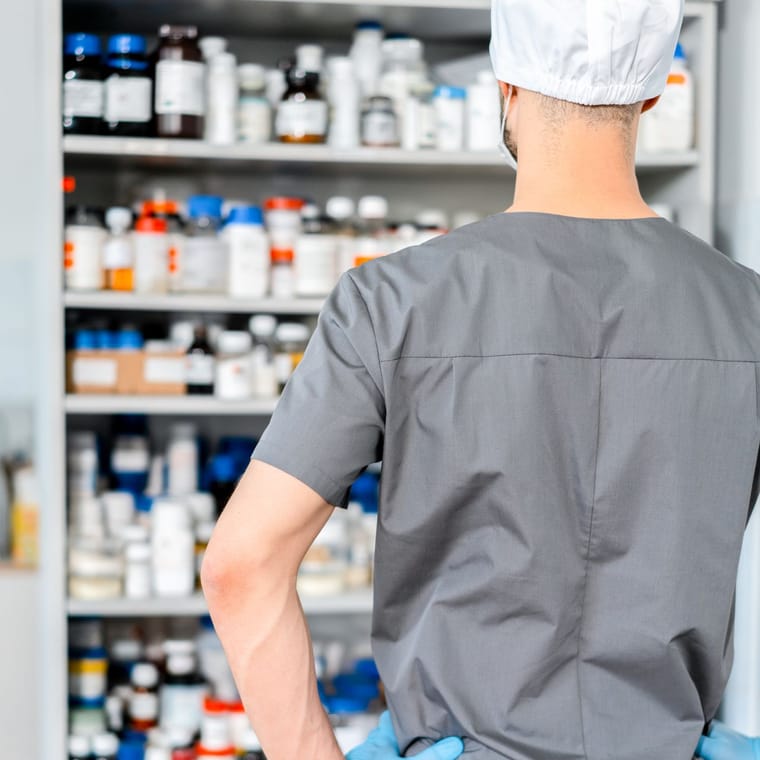A pharmacist facing shelves of prescription medication